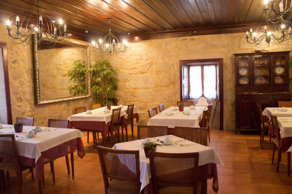 un restaurante con mesas y sillas blancas y un espejo en Boega Hotel, en Vila Nova de Cerveira