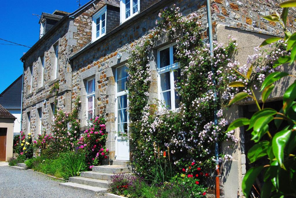 una casa de piedra con flores a un lado. en Maison Voie Verte en Bion