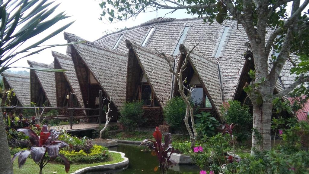 una casa con un techo deformado en un jardín en Bali Eco Village, en Plaga