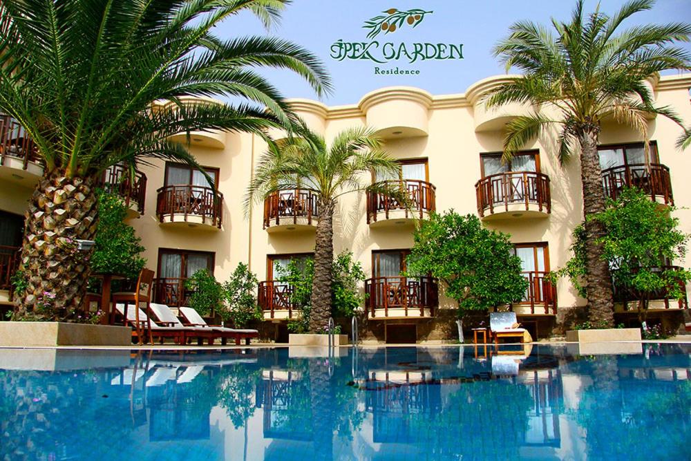 a hotel with palm trees in front of a swimming pool at Ipek Garden Palace Residence in Yaliciftlik