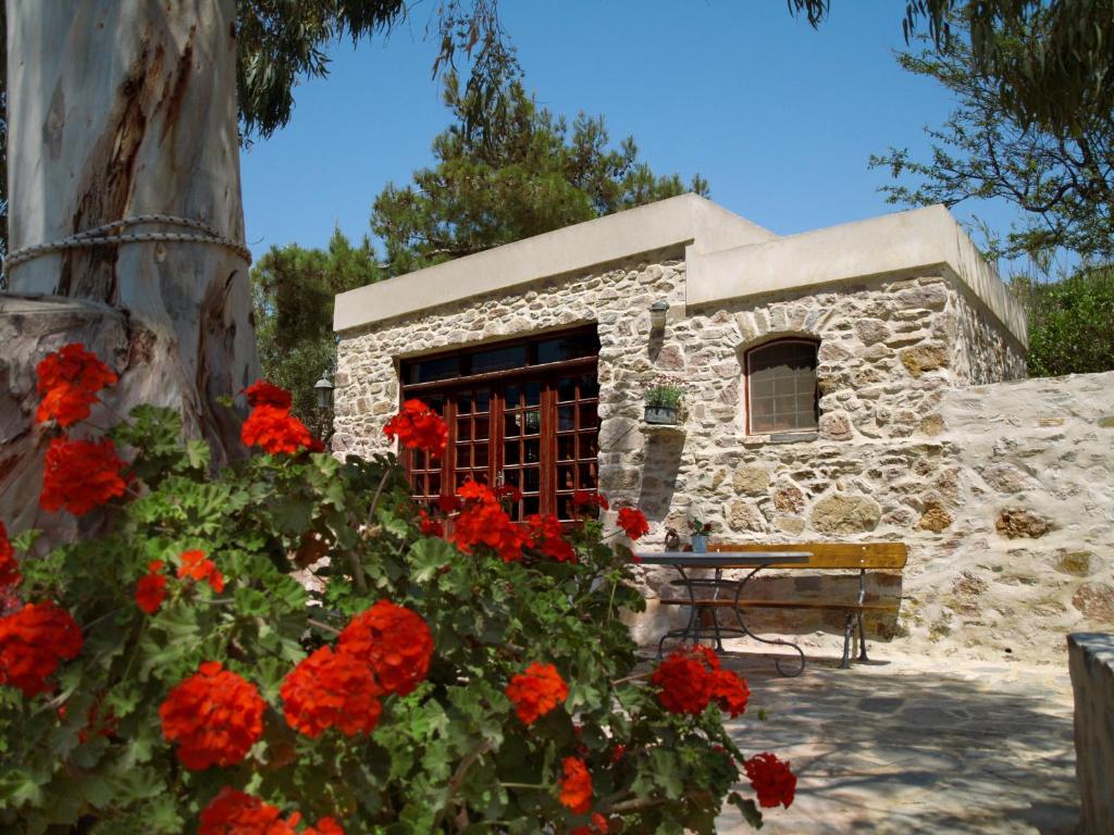 un edificio de piedra con flores rojas delante de él en Chroussiano Farmhouse, en Chrousa