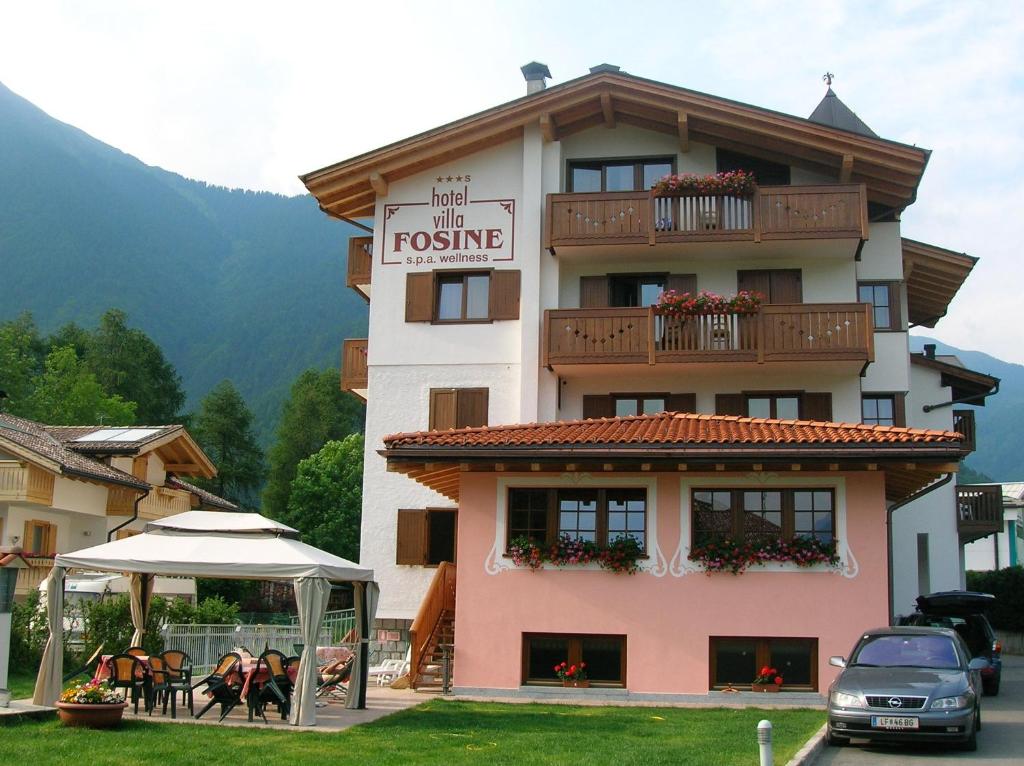 a building with a table and chairs in front of it at Hotel Villa Fosine in Pinzolo