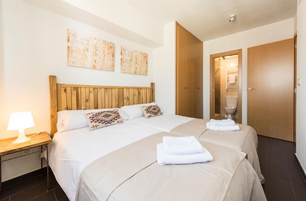 マドリードにあるLa Gata Madridの木製ヘッドボード付きのベッドルームに白いベッド2台が備わります。