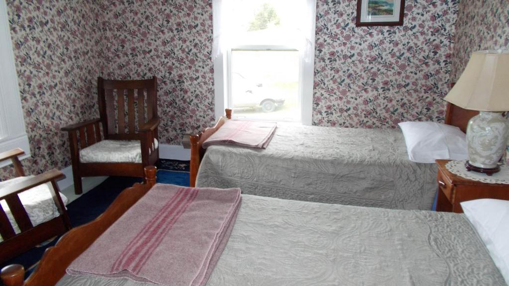 a room with two beds and a chair and a window at Margaree Harbour View Inn B&B in Margaree Harbour