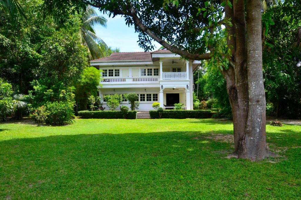 a white house with a tree in the yard at Baan Khun Nang Colonial Residence in Mae Nam