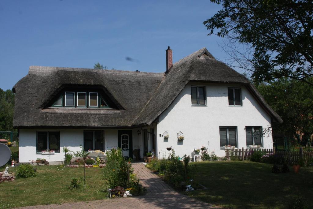 ein weißes Haus mit einem Strohdach in der Unterkunft Haus Bernsteinchen in Gustow