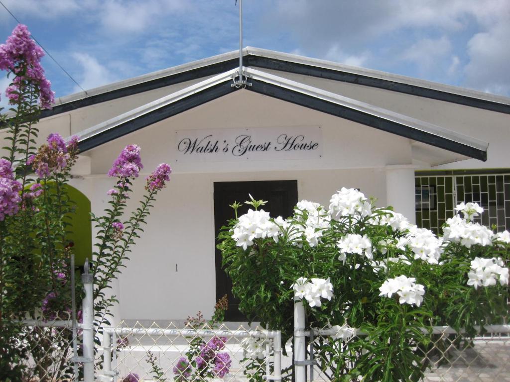 un edificio blanco con flores delante en Walsh's Guesthouse, en Christ Church