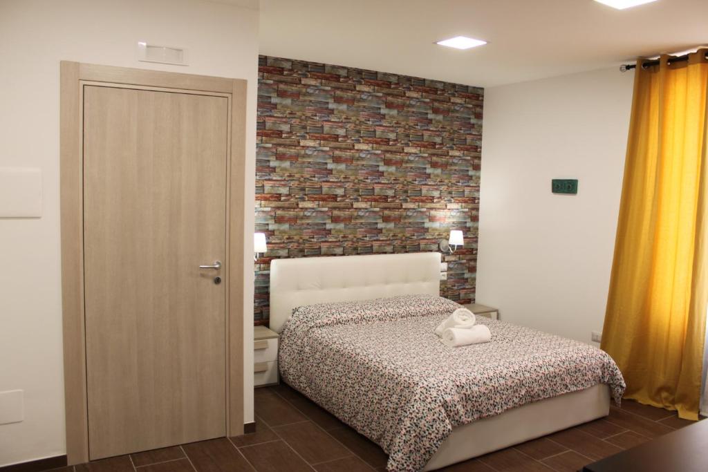 1 dormitorio con cama y pared de ladrillo en Casa Vacanze A Due Passi, en Grammichele