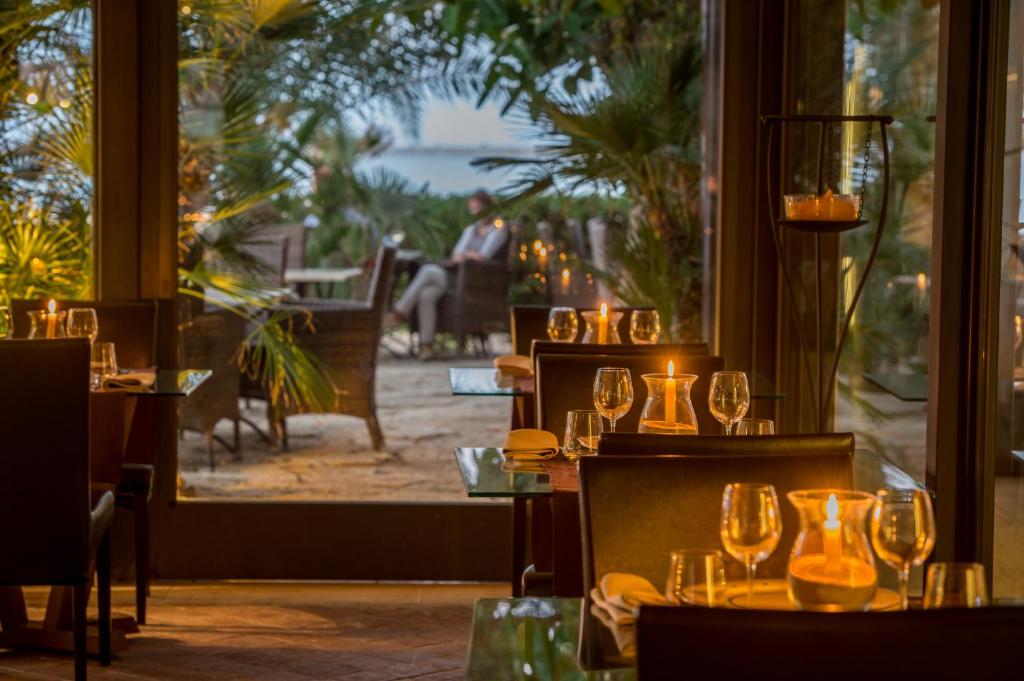 a restaurant with a table with wine glasses in front of a window at Hotel Capo San Vito by Geocharme in San Vito lo Capo