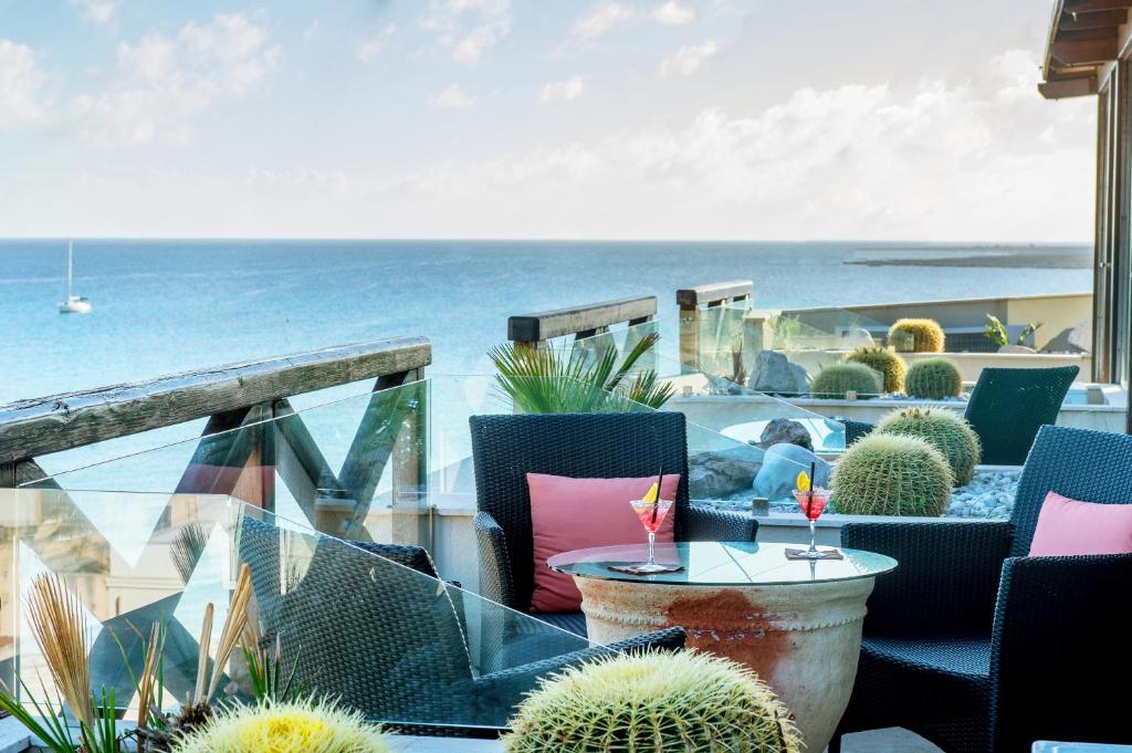 a view of the ocean from a balcony with chairs and cactus at Hotel Capo San Vito by Geocharme in San Vito lo Capo