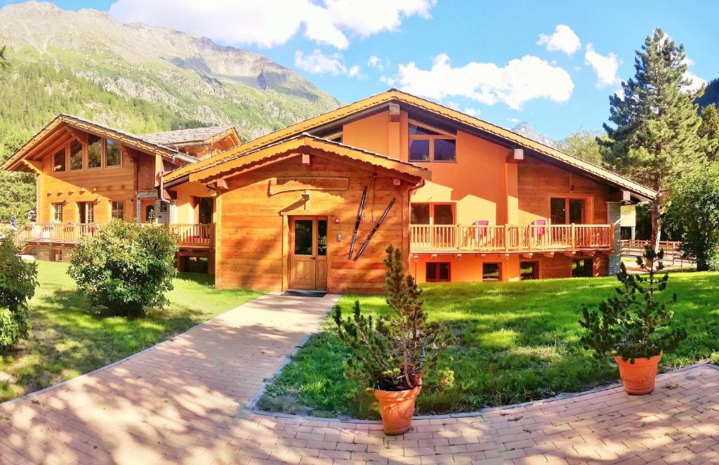 a log home with a mountain in the background at Chalet Alpina Hotel & Apartments in La Thuile