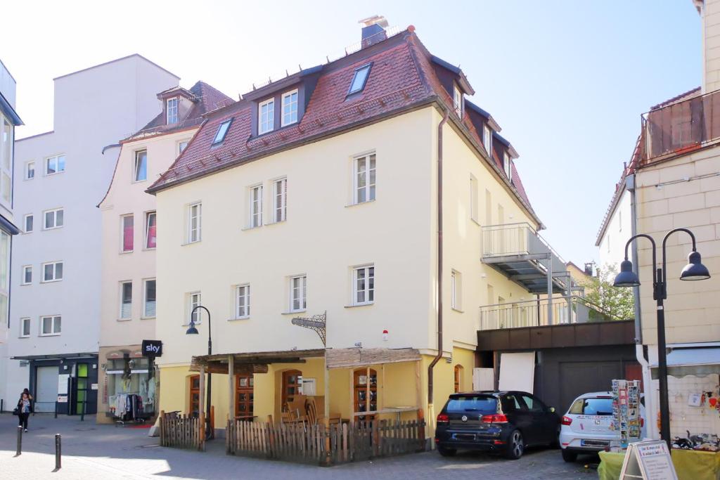 a white and yellow building with cars parked in front of it at Ferienwohnungen-Gmuend Stadtherberge Mühlbergle in Schwäbisch Gmünd