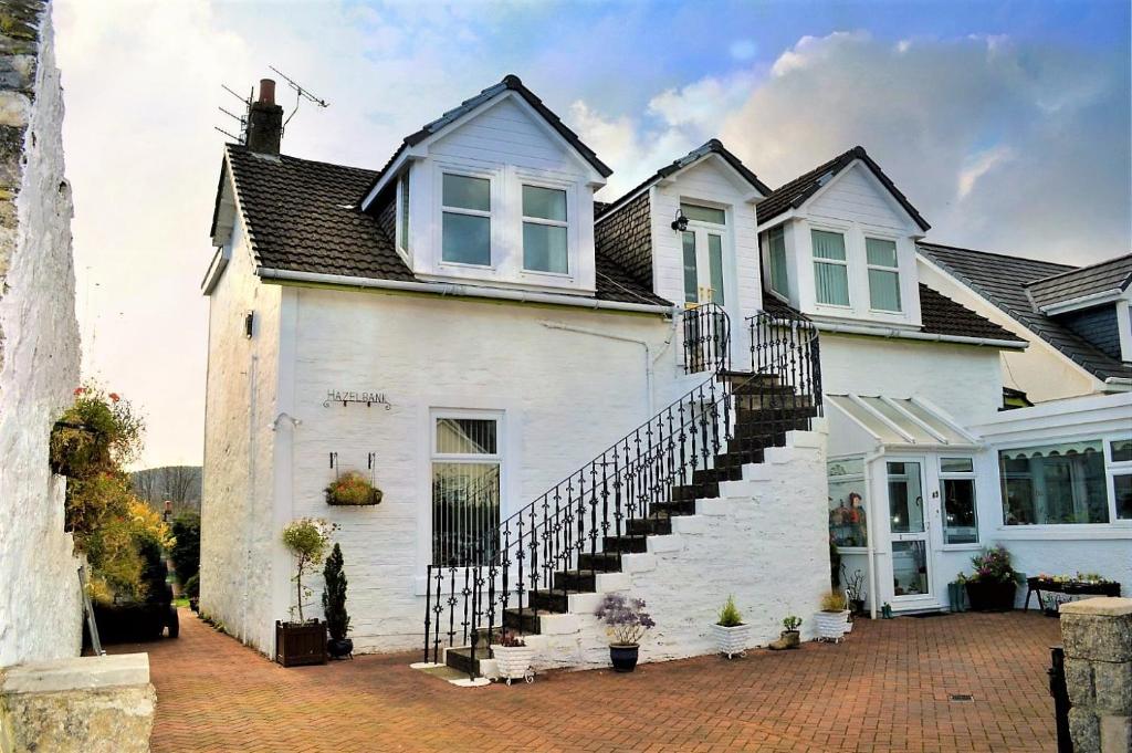 una casa blanca con una escalera delante en Hazel Bank Villa Apartment, en Dunoon