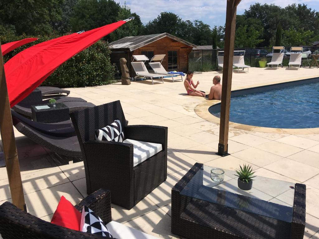 a patio with chairs and a pool with a red umbrella at Logis Hôtel & Spa Déjeunez Sous L'Arbre in Rousset