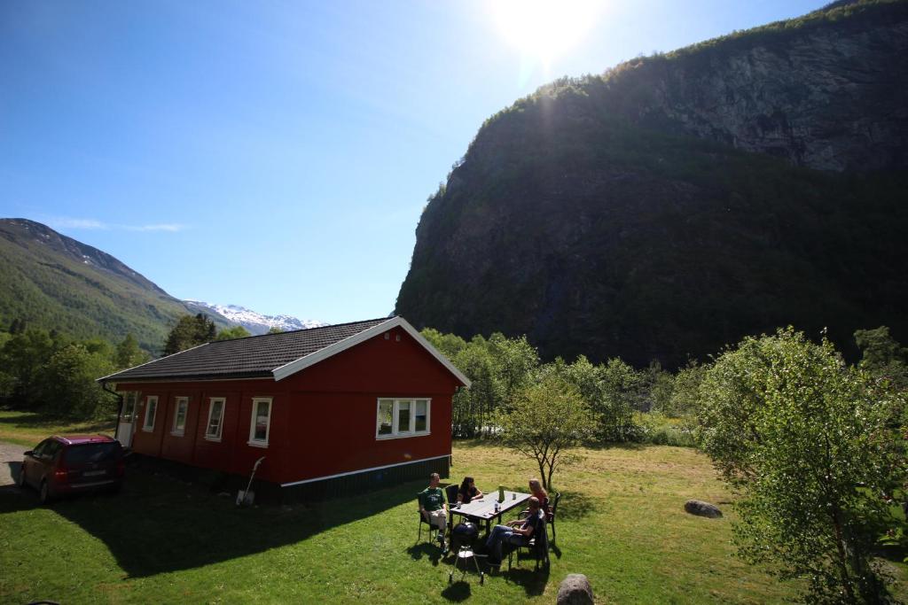 a red house with people sitting at a table in front of it at Steinshølen Holiday Home in Flåm