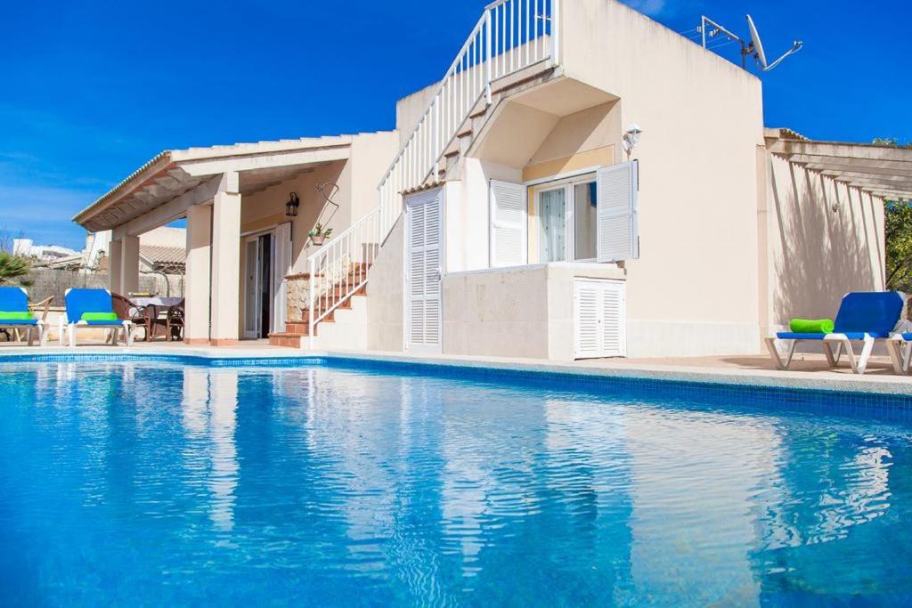 a villa with a swimming pool in front of a house at Can Content - Playa de Muro in Muro