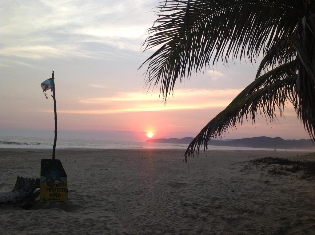 een zonsondergang op het strand met een vlag in het zand bij Casa de la Tortuga in Zihuatanejo