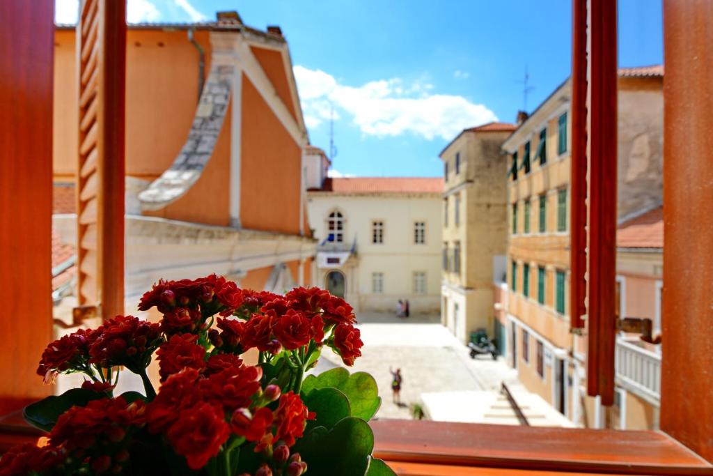 un jarrón de flores rojas sentado en un alféizar de la ventana en Apartment Martina, en Zadar
