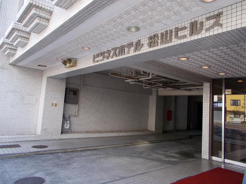 une entrée à un bâtiment avec un panneau sur celui-ci dans l'établissement Hotel Matsuyama Hills, à Matsuyama