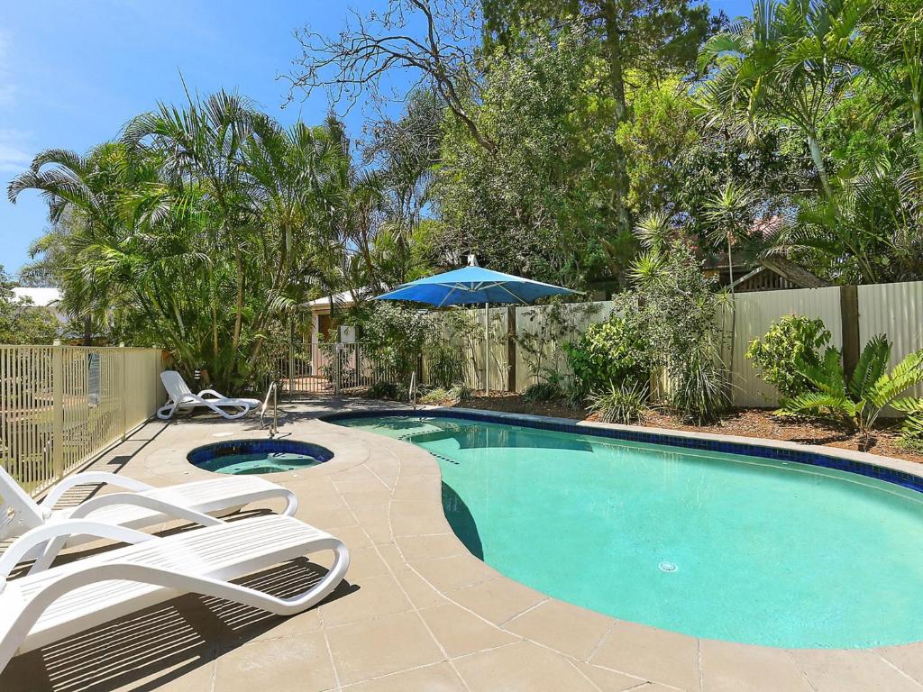 a swimming pool with two chairs and an umbrella at Chez Noosa Resort Motel in Sunshine Beach