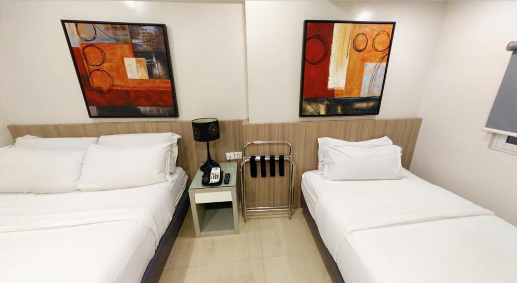 2 Betten in einem Zimmer mit Gemälden an der Wand in der Unterkunft Z Pad Residences in Tacloban