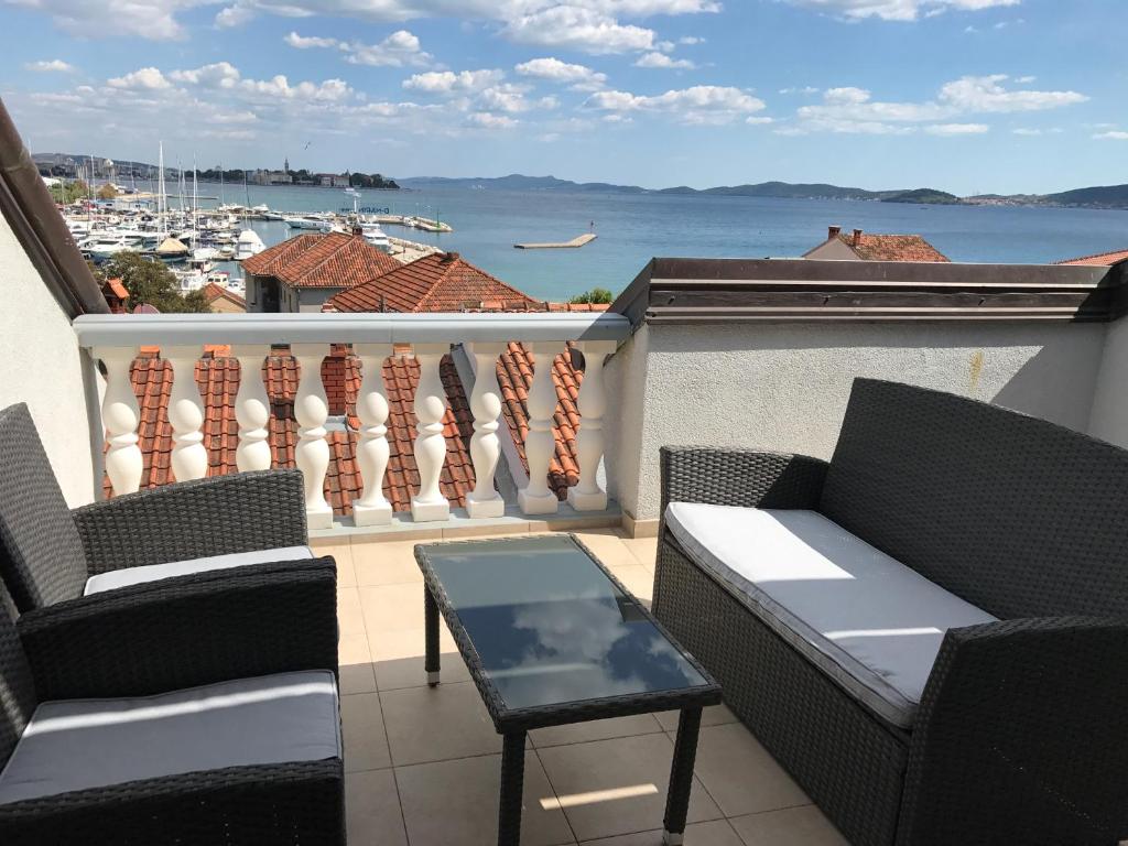 d'un balcon avec deux chaises, une table et une vue sur l'eau. dans l'établissement Apartments Puntamika, à Zadar