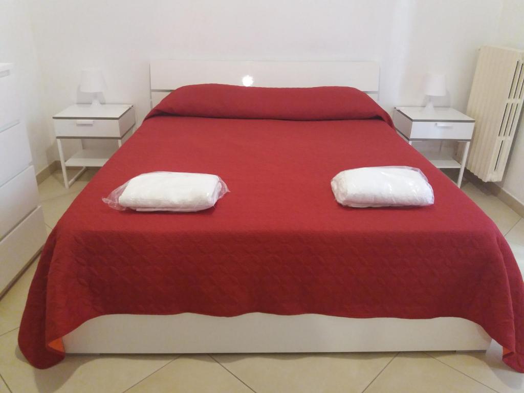 een slaapkamer met een rood bed en 2 nachtkastjes bij Le cisterne Holiday Home in Manfredonia