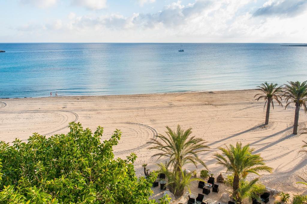 an empty beach with palm trees and the ocean at Hotel Capo San Vito by Geocharme in San Vito lo Capo