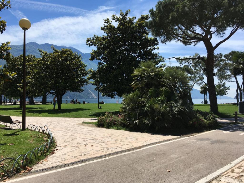 eine Straße mit einem Park mit Bäumen und einer Straßenbeleuchtung in der Unterkunft Appartamento al Lago in Riva del Garda