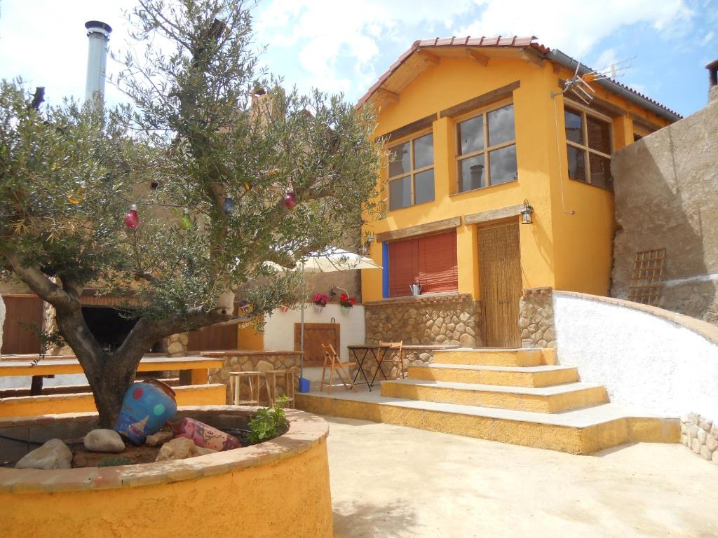 Olvés的住宿－Casa Isabel，前面有一棵树的黄色房子