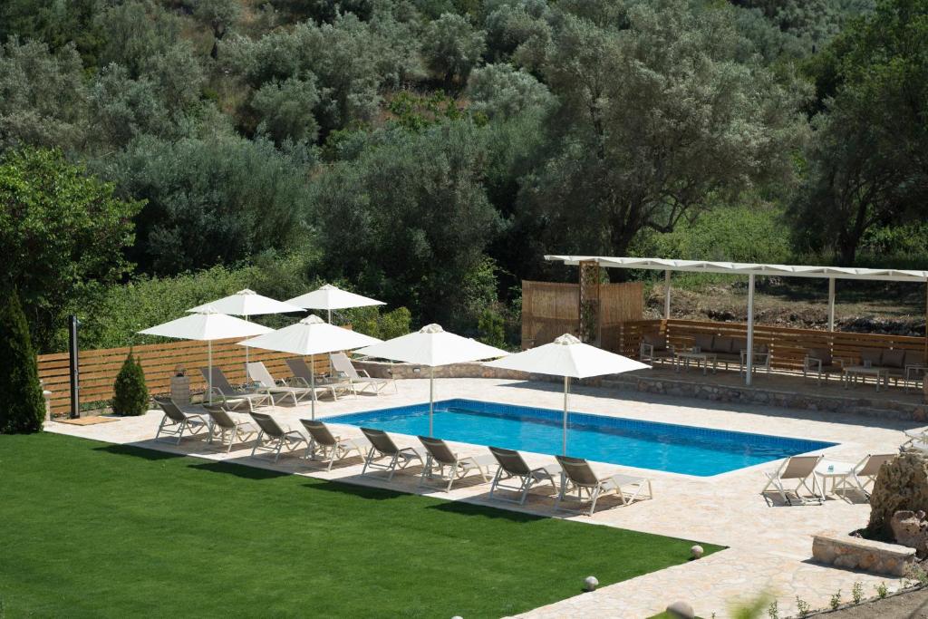 a swimming pool with white umbrellas and lounge chairs and a pool at Gea Villas in Lygia