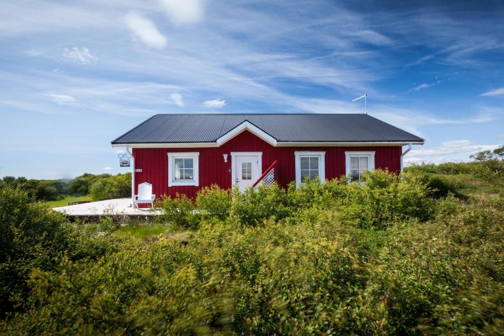 una casa roja con un techo negro en un campo en Stóraborg Holiday Home, en Storaborg