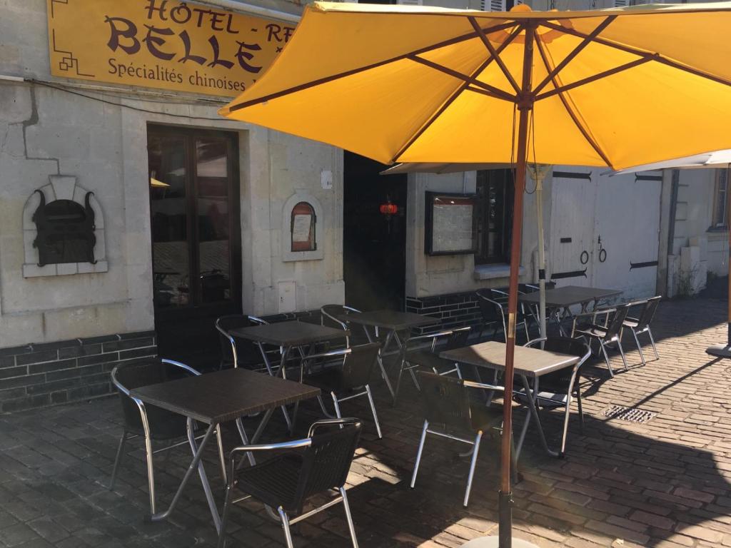 een groep tafels en stoelen met een gele paraplu bij Belle d'Asie in Longué