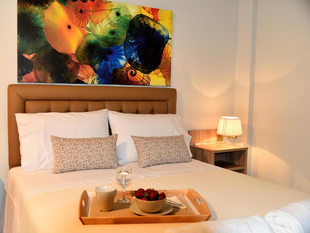 アテネにあるDaphne's Apartmentのベッドに飾られたフルーツのトレイ(絵画付)