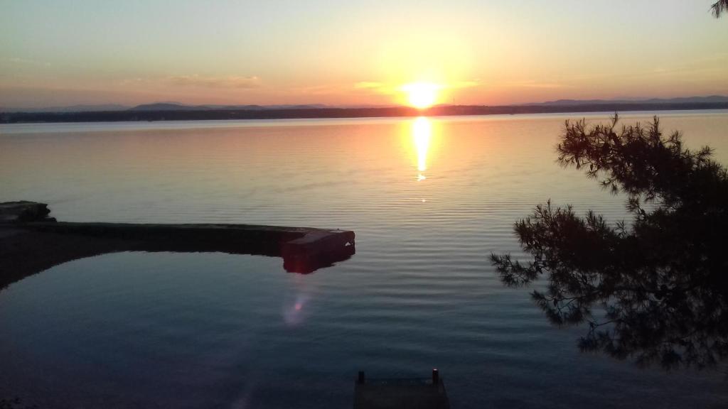 una puesta de sol en un lago con un reflejo en el agua en Apartments Ori, en Tkon