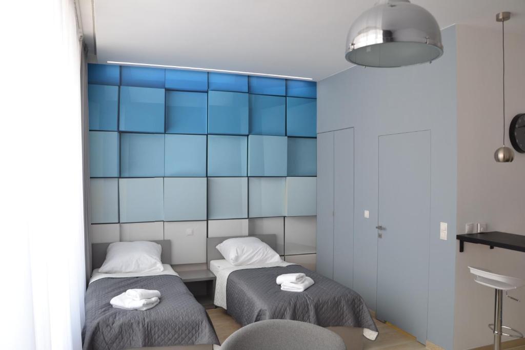 two beds in a room with blue tiles at Apartamenty Krawiecka in Zielona Góra