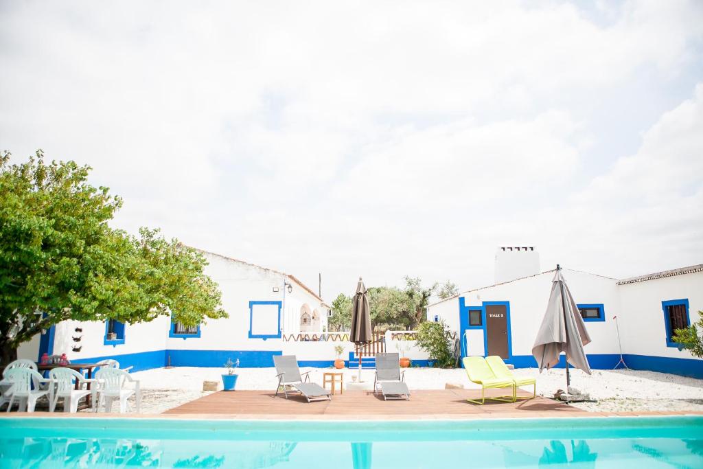 a swimming pool with chairs and an umbrella and a table at Carrança Lounge in Évora