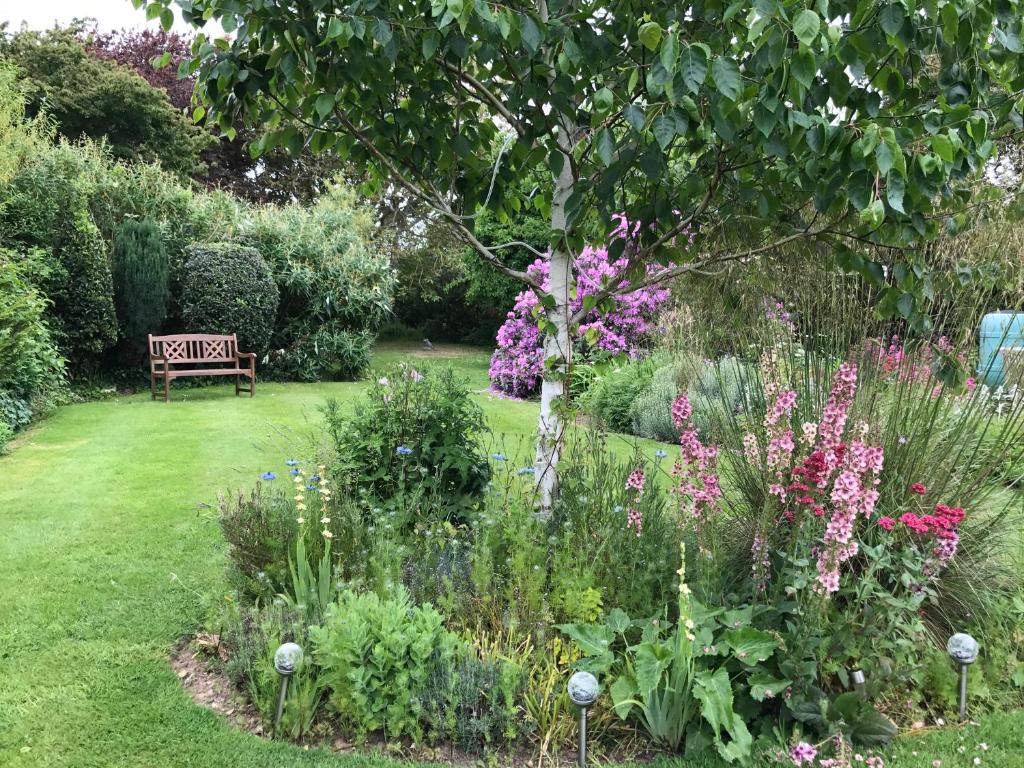 a garden with a bench and some flowers at The Coast Yard B & B and Garden Chalets in Selsey