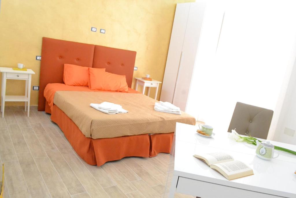 una camera da letto con letto con testiera arancione e scrivania di Il Cantastorie Salentino a Gallipoli