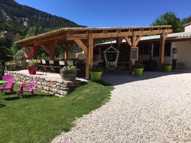 un pavillon avec des chaises roses et un mur en pierre dans l'établissement Camping Calme et Nature, à Castellane