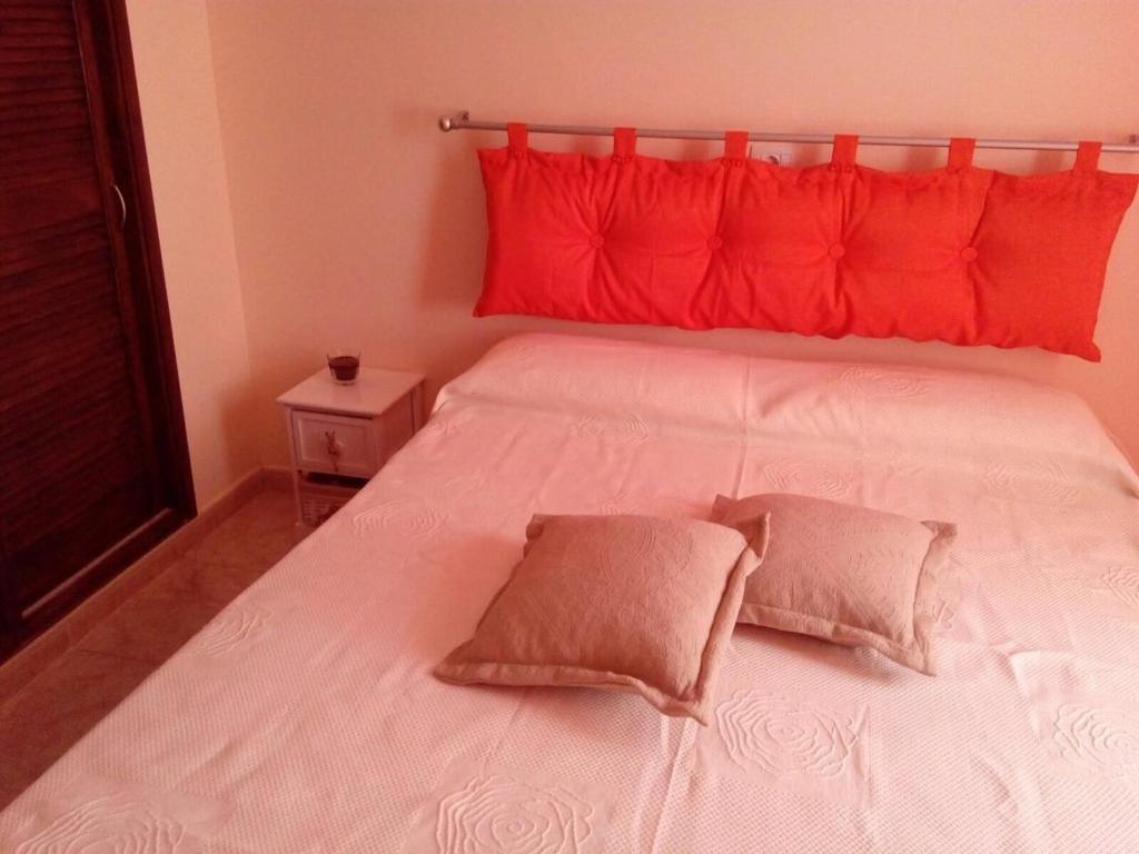a white bed with red pillows on top of it at Sweet Home San Blas in San Miguel de Abona