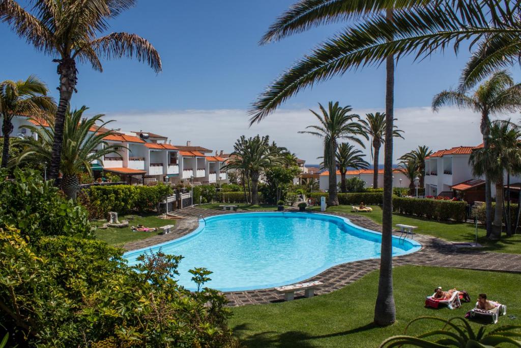 una imagen de una piscina en un complejo con palmeras en Apartamento Salinas 2, en Los Cancajos
