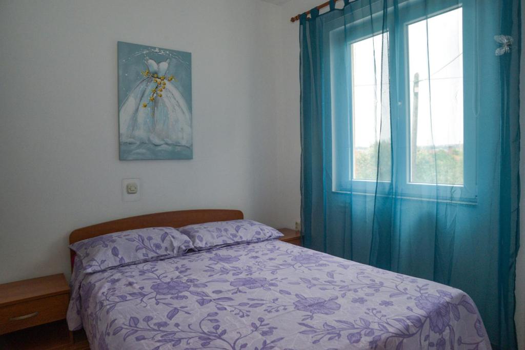 sypialnia z łóżkiem z niebieskimi zasłonami i oknem w obiekcie Latmo Apartment Zadar w mieście Zadar