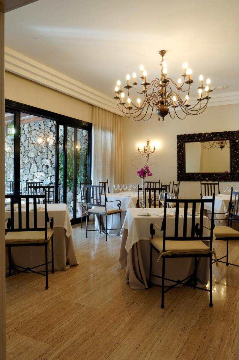 Un comedor con mesas y sillas y una lámpara de araña. en Villa VIK - Hotel Boutique, en Arrecife