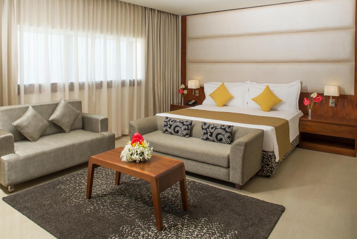 a bedroom with a bed and a couch and a table at The Raviz Calicut in Kozhikode