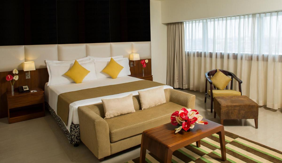 a bedroom with a large bed with a couch and a chair at The Raviz Calicut in Kozhikode
