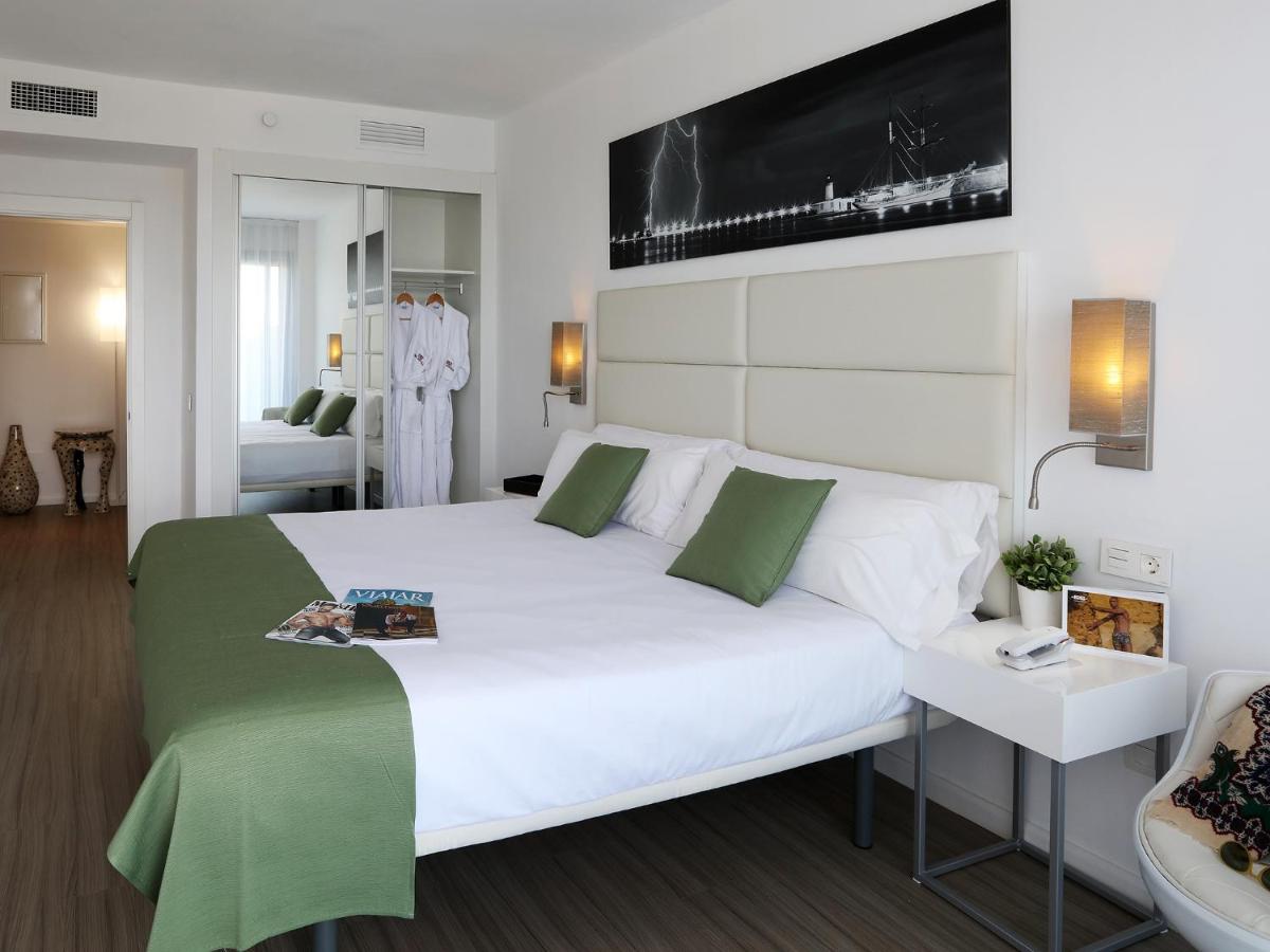 1 dormitorio con 1 cama blanca grande con detalles verdes en Axel Beach Ibiza - Adults Only, en Bahía de San Antonio