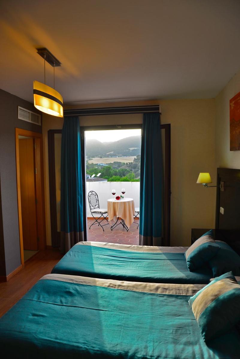 Un dormitorio con dos camas y una mesa y una ventana. en Hotel & Spa PLAZA Arriate, en Arriate