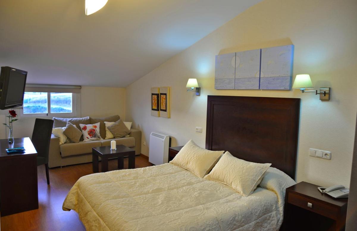 Un dormitorio con una cama y una sala de estar. en Hotel & Spa PLAZA Arriate, en Arriate