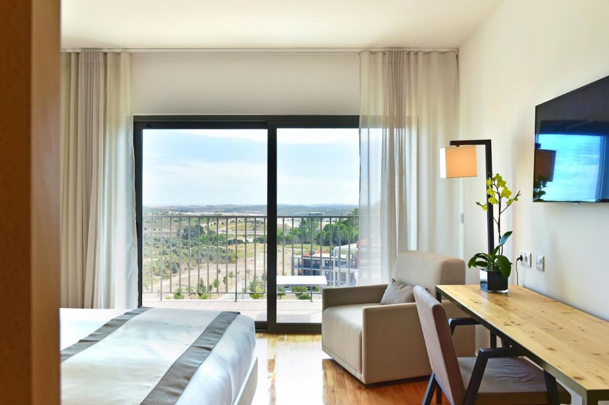 um quarto de hotel com uma cama, uma escrivaninha e uma janela em Algarve Race Resort - Hotel em Montes de Cima